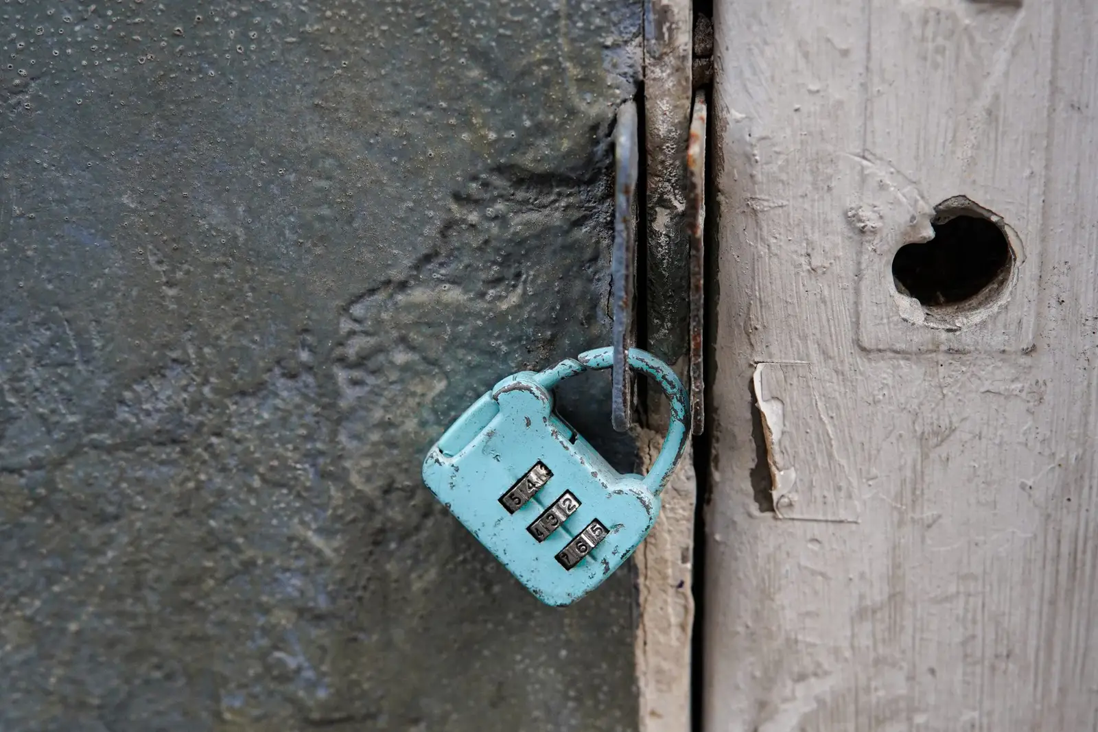 A combination padlock on an old door, representing the lockbox codes rental scammers use to fake self-guided tours